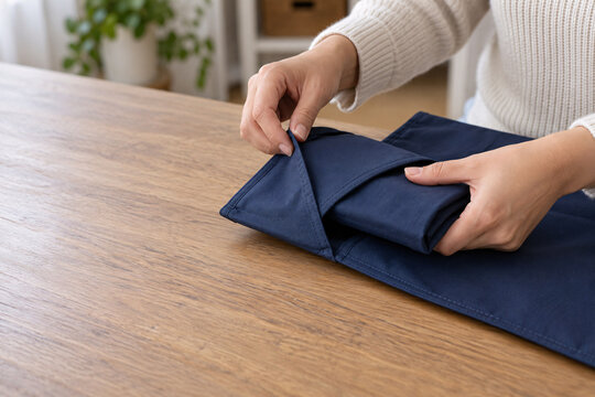 Hands Tucking Folded Cloth Beneath a Reusable Mailer Flap