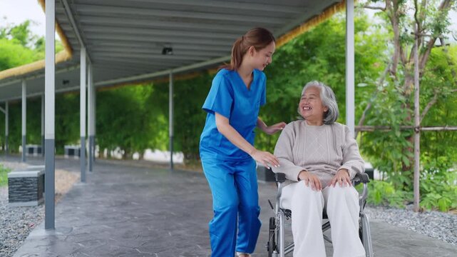 Nurse pushes elderly woman in wheelchair under shelter. Woman smiles warmly, enjoying gentle outdoor outing. Caregiver kneels beside her