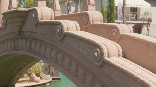 Close view of sculpted scrollwork along an arched garden bridge with turquoise water underneath