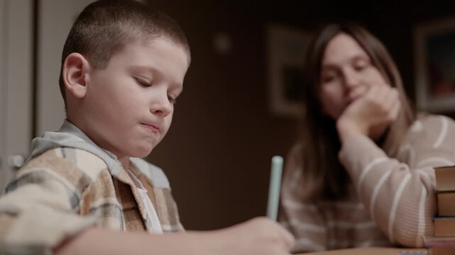 Schoolboy doing homework while mother corrects him. Parenting education discipline learning concept