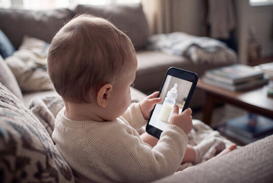 Baby boy looking at a bottle of milk on a phone screen