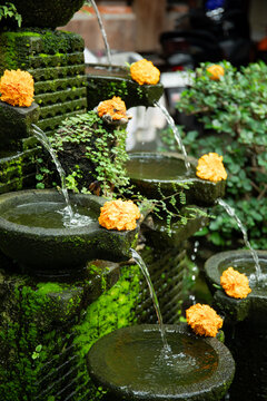 Water flows from stone fountain decorated with orange marigold flowers