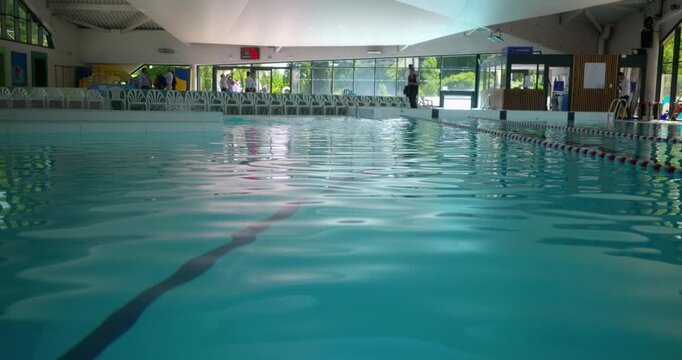 Calm water surface of an indoor swimming pool, low angle slow motion