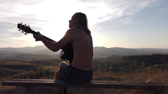  Slow motion view of musician playing guitar on in mountains during sunset