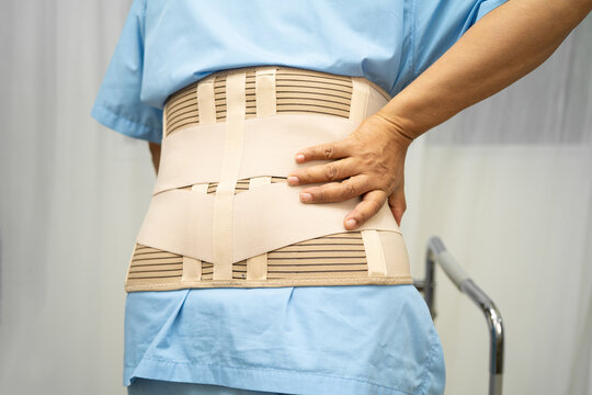 Asian senior pain back wearing elastic support belt with walker.