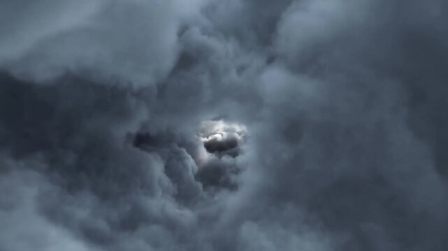 Dark storm clouds shift around a bright opening as sunlight filters through the sky
