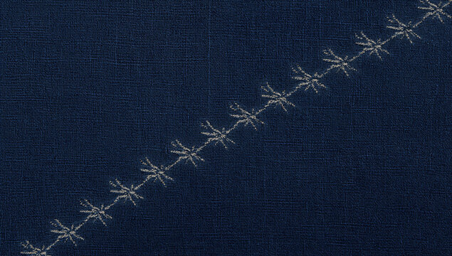 紺色の織物を斜めに横切る白い刺繍の連続模様