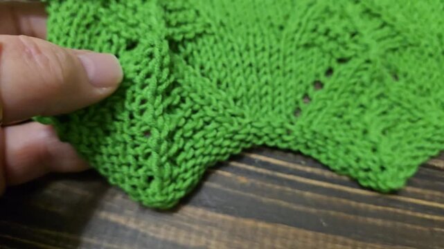 The process of knitting a multicolored openwork yoke for a jumper or cardigan. The raised pattern is on circular needles, and the work is placed on a dark wooden table.
