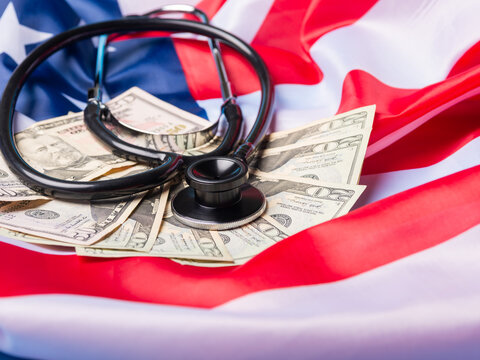 Black Stethoscope on US Dollar Bills and American Flag Representing Healthcare Costs