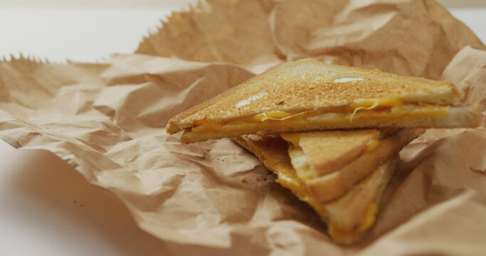 Image of close up of toasted cheese sandwiches on brown paper over grey background