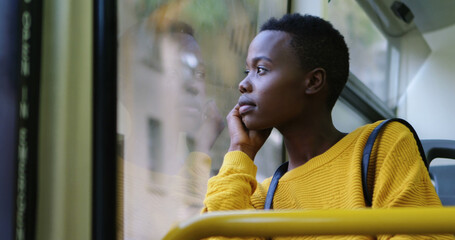 Young African American woman gazes out a bus window, deep in thought © WavebreakMediaMicro