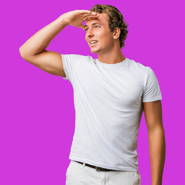 Man caucasian young t shirt looking far away, look happy, hand raised in search, searching and smiling studio portrait capturing a hopeful, forward gaze