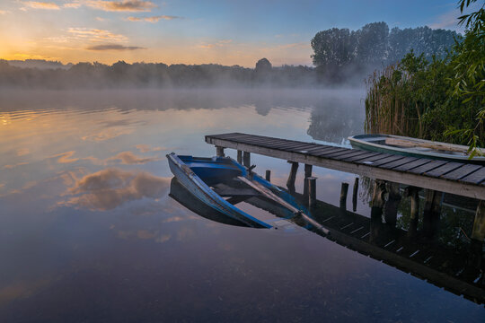 Sunken boat beside Wooden jetty on Dietlhofer See lake at sunrise