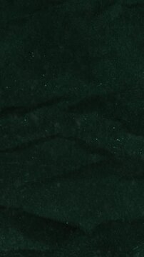 Vertical video: Soft light shifts and tiny jolt causing dark green surface revealing subtle texture