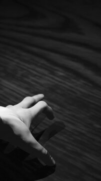 Vertical video: Hand entering lower-left lifting finger sliding grasping testing wood casting shade