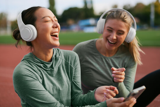 Two women laughing together during a break at the running track