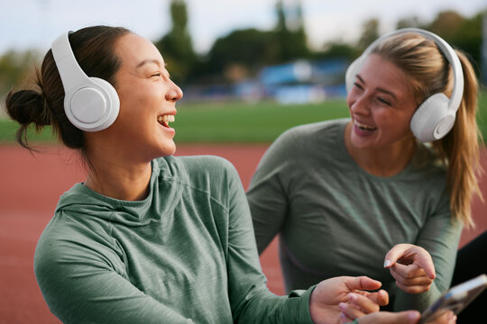 Two women smiling and talking during an outdoor workout break