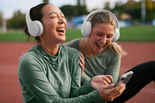 Two women laughing while checking a phone after exercise