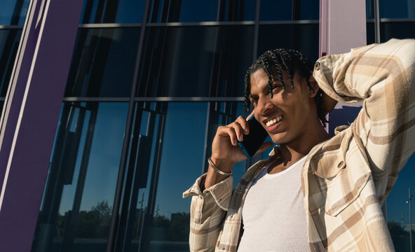 Young cuban man smiling talking on smartphone