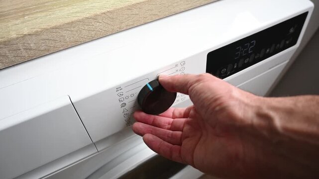 Close up of a person selecting a washing program on a washing machine control panel. Household chores, laundry routine and domestic cleaning concept.