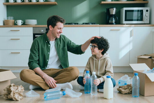 Caucasian young adult man and child sorting plastic bottles for waste recycling at home. Concept suitable for ecological education and sustainability campaigns