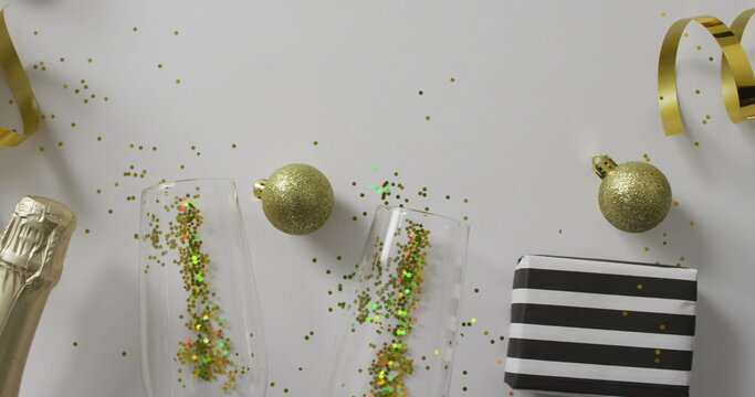 Image of christmas baubles and new year's eve champagne and party streamers