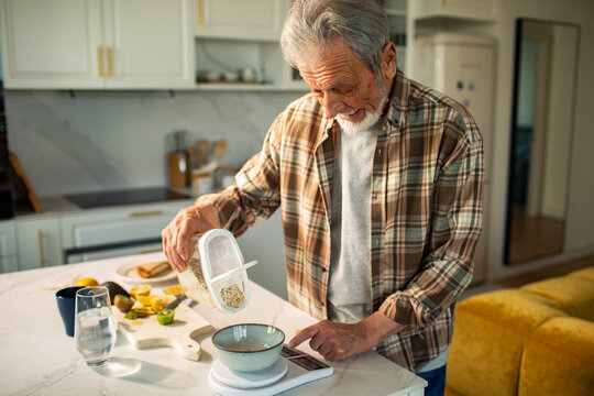 Senior man weighing oats on a digital kitchen scale