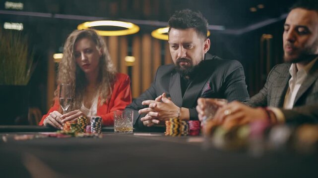 Dealer handing out cards at a poker table. Players studying their hands in a casino
