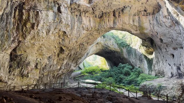 Devetashka Cave massive karst cavern entrance arches with green vegetation inside giant stone halls natural landmark travel in Bulgaria stock footage