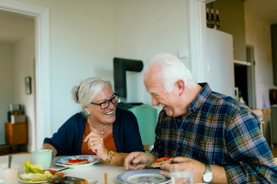 Senior couple laughing while sharing a meal at home