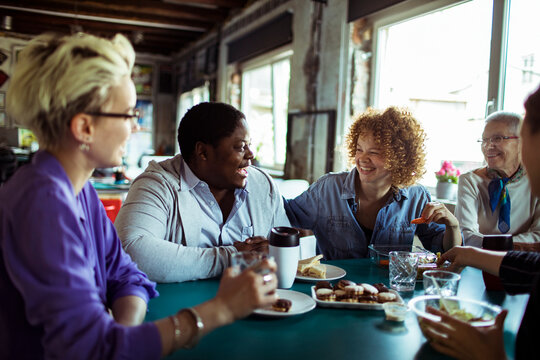 Friends laughing over lunch at a cafe table