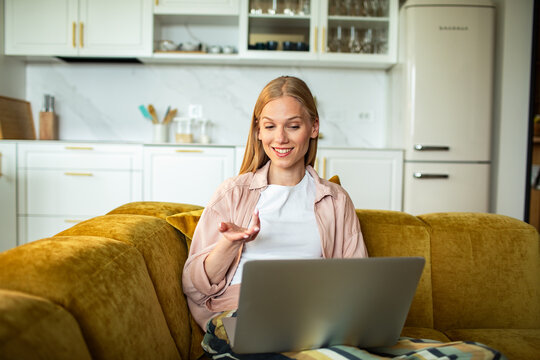 Smiling woman video chats on laptop at home