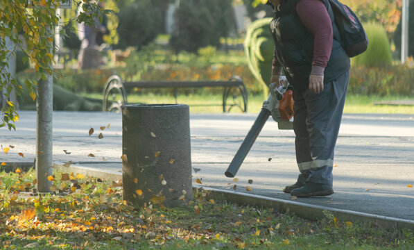 Worker Using Power Leaf Blower Near Park Urn