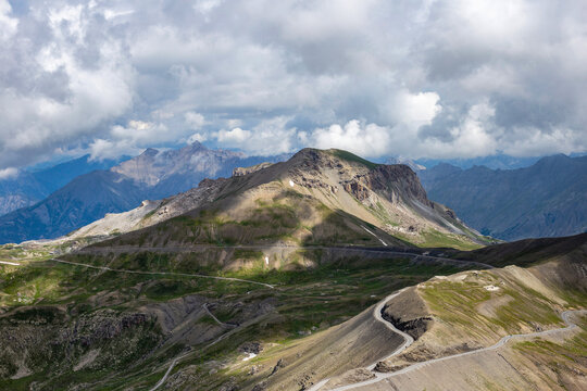 Winding asphalt road climbing up the majestic Col de la Bonette pass in the French Alps under a cloudy sky