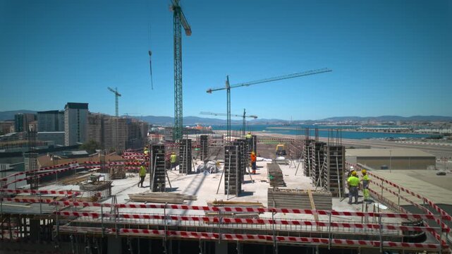 Construction worker team installs concrete formwork panels on a building site in timelapse while a tower crane lifts materials and crews secure structural pillars on the upper floor slab