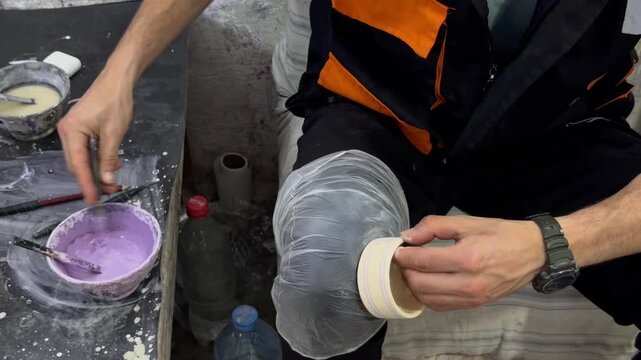 A male artisan carefully paints delicate pattern details onto a ceramic bowl with a brush in a workshop, traditional pottery craft, creative handmade art, authentic local master skill.