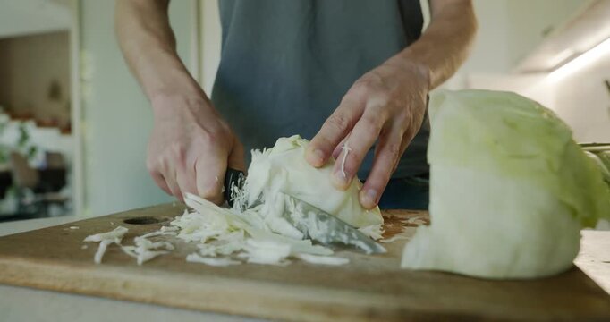 Close-up male hands cut cabbage with knife on wooden cutting board. 4K 10-bit