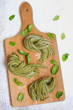 Fresh green basil tagliatelle pasta on wooden board