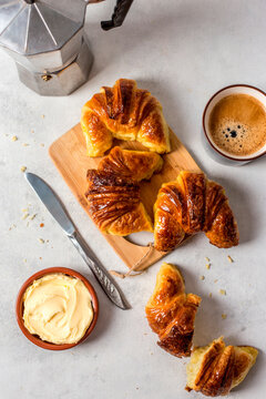 Croissants with coffee and butter on wooden board