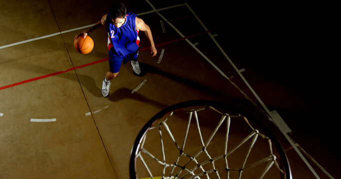 Young Caucasian man playing basketball indoors, with copy space