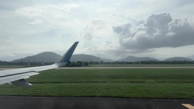 Airplane wing and winglet on runway during takeoff roll with mountains behind