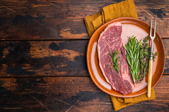 Uncooked sirloin cut, raw beef steak known for its tenderness and robust flavor.  wooden background. top view