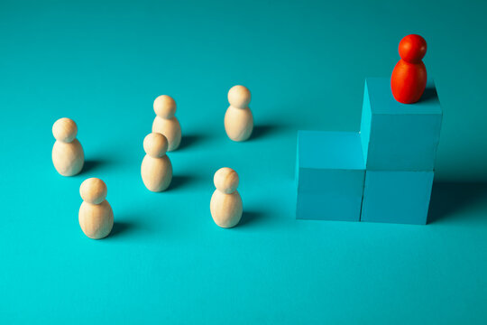 Leadership concept. The red leader stands on top of the podium among the other figures.
