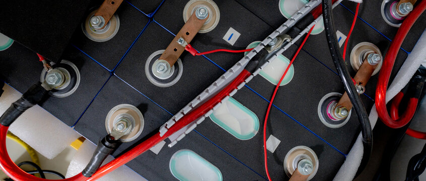 Electric vehicle lithium NMC battery pack with interconnected cells, copper busbars and high voltage cables, photographed indoors for EV energy storage, automotive power and rechargeable technology.