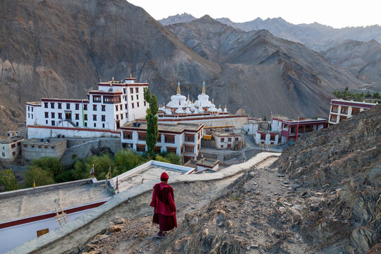 Monk in red robe walking down a mountain path toward Yuru Monastery, Ladakh, Lamayuru, India