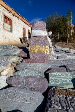 Mani stone with gold mantra and white scarf among carved stones near Yuru Monastery, Ladakh, Lamayuru, India