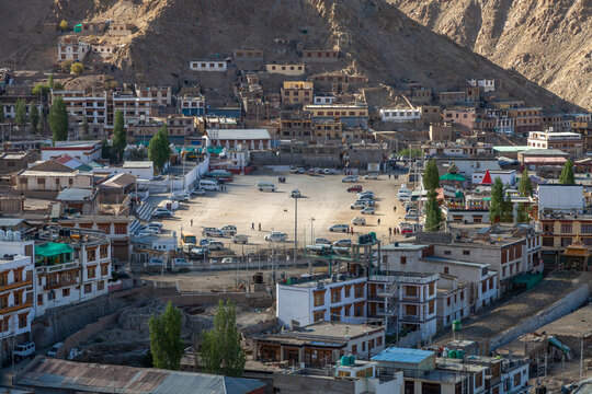Town square with parked cars surrounded by houses on a rocky hillside, Ladakh, Leh, India