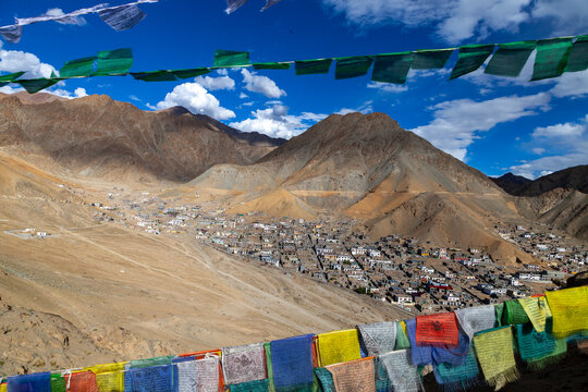 Prayer flags framing a town at the foot of dry mountains, Ladakh, Leh, India
