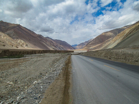 Scenic road through mountainous landscape under cloudy sky