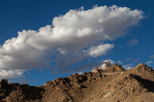 Hilltop fort on a rocky ridge under a big white cloud and blue sky, Ladakh, Leh, India